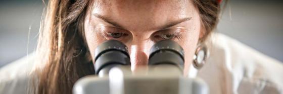 scientist peering into microscope